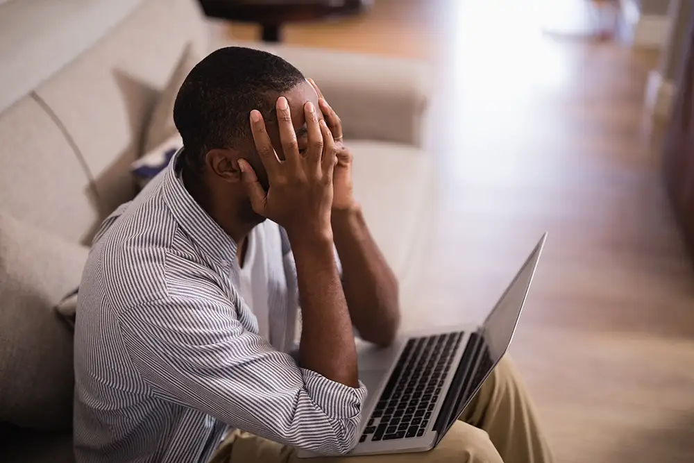 A frustrated jiu jitsu school owner in front of his laptop who desperately needs jiu jitsu marketing
